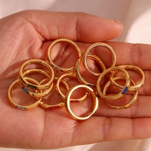 Close-up of gold-plated rings with rectangular multi-color zircon gemstones on fingers