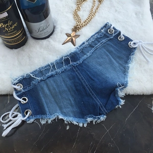 Dettaglio di pantaloncini denim a vita bassa con occhielli in metallo e orlo a vivo