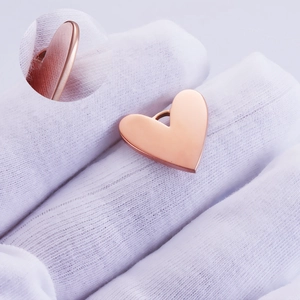 Polished rose gold heart pendant with round corners shown on hand with a detail inset view