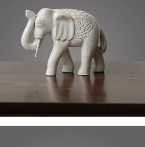 Détail d'une figurine d'éléphant blanc avec gravures florales sur bois foncé