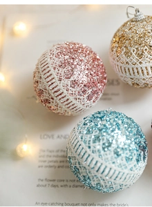 Close-up of glittery Christmas foam balls with white lace trim and decorative metal loops