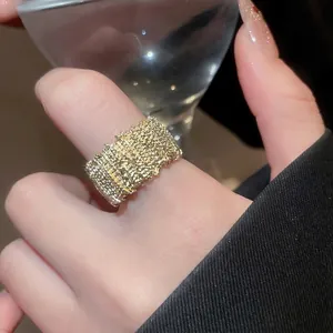Gold wide band ring with irregular lava texture for women on finger by a glass