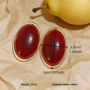 Detail of vintage oval resin earrings with gold alloy frame on textured beige paper