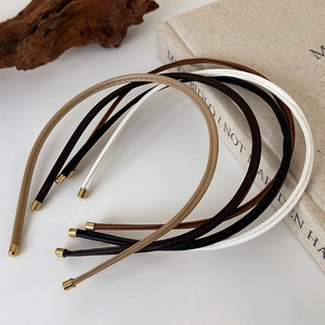 Detail of four-color leather slim headbands with gold metal tips on minimalist books