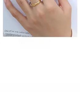 Detailed view of a gold-plated braided spiral ring worn on the finger with textured finish