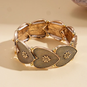 Detailed close-up of retro gold heart modules with embossed flower patterns on the bracelet