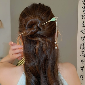 Détail d'une épingle à cheveux chinoise avec feuilles vertes, perles et glands dorés
