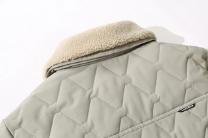 Detail of grey-green quilted jacket with faux shearling collar and wave patterns