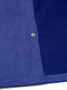 Detailed close-up of dark and royal blue suede fabric texture with silver metal snap button