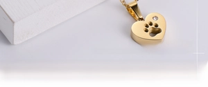 Détail d'un pendentif cœur doré avec une empreinte de patte creuse et petit cristal