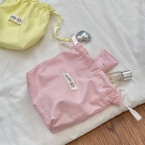 Detailed view of pink and yellow drawstring fabric pouches with smooth ribbon ties