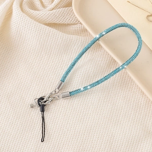 Detail of luxury blue rhinestone phone lanyard with metal chain on a white tray