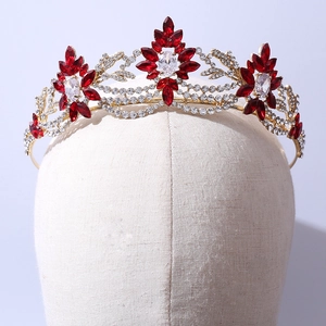 Elegant gold bridal crown with floral motifs, red crystals, and zircon on a mannequin