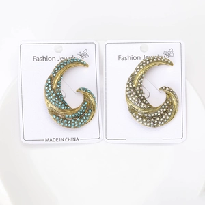 Close-up of vintage geometric C-shaped crystal brooches in blue and white rhinestones