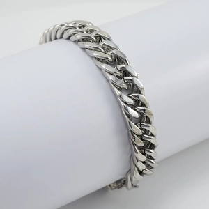 Polished silver stainless steel Cuban link bracelet for men displayed on a white stand