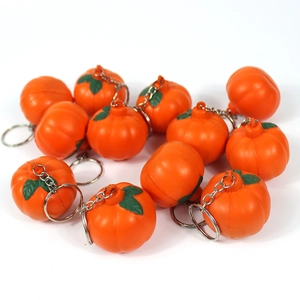 Close-up of 11 mini orange pumpkin keychains made of soft silicone with green stems