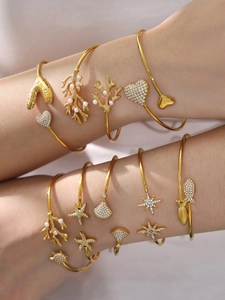 Détail de bracelets dorés aux motifs marins avec perles et zircons scintillants