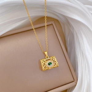 Detail of vintage gold necklace with hollow pattern and green gemstone on silk