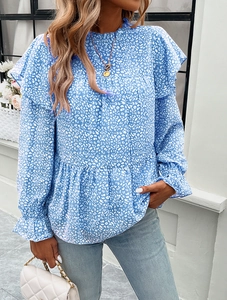 Detail of blue floral blouse featuring elegant ruffled edges and long sleeves