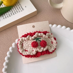 Détail d'une pince à cheveux cerise tricotée main sur assiette avec décor chaleureux