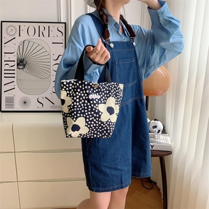 Borsa da pranzo in tela floreale a pois blu scuro tenuta da una modella in ambiente domestico