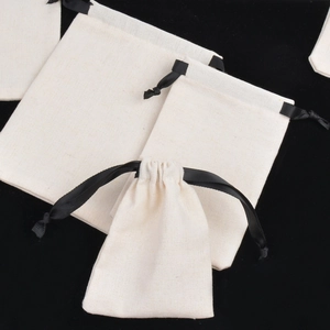 Detailed view of beige cotton linen jewelry pouches with black drawstrings in various sizes