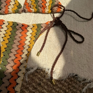 Détails du bikini au crochet avec motif ondulé et liens tressés aux pendentifs dorés