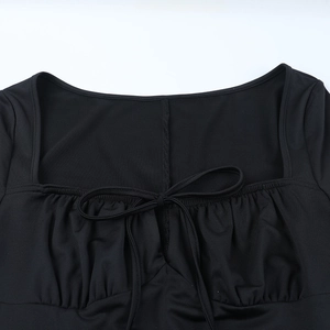 Détail de robe noire à manches longues avec décolleté carré et nœud papillon à cordon