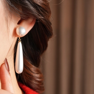 Close-up of elegant resin teardrop pearl earrings with gold link on a model's ear