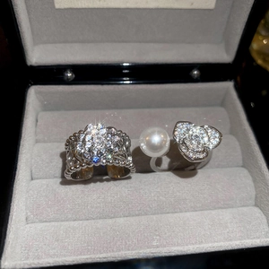 Détail de bagues argentées avec fleur de camélia et perle dans un écrin à bijoux