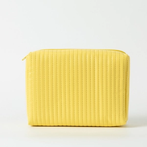 Detail of yellow PU leather makeup bag featuring vertical perforated stripe patterns