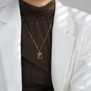 Elegant gold titanium necklace with a black rectangular rose pendant on a model