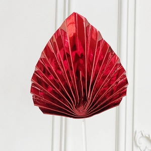 Close-up of a glossy red fan-shaped cake topper with a metallic origami finish