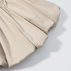 Detailed close-up of light beige fabric hem showing smooth texture and ruffled design