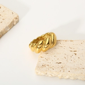 Macro shot of 18K gold croissant ring with twisted texture on a natural stone base