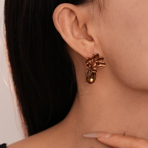 Vintage bronze flower earrings with brown teardrop zircon drops on a model's ear