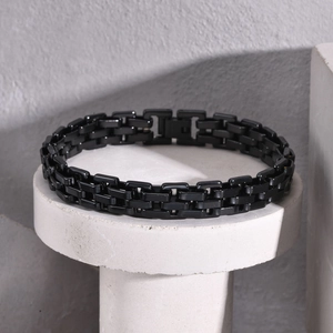 Close-up of black metallic chain link bracelet on a minimalist concrete pedestal