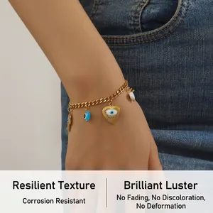 Detail of golden Hamsa Hand and Evil Eye heart charms on a Cuban chain bracelet