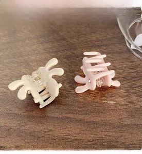 Detail of mini acetate rabbit hair claws with golden metal springs on wooden surface