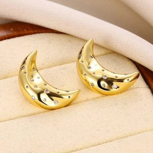 Macro shot of gold crescent moon earrings with inlaid zircons in a jewelry box