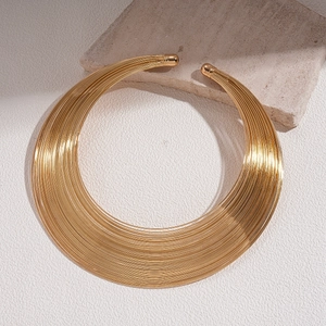Detailed view of wide gold multi-strand metallic choker on a textured stone background