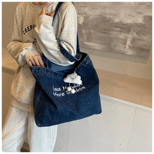 Detail of embroidered lettering on denim tote bag with cute plush cloud charm