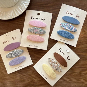 Detail of floral fabric hair clips in pastel colors displayed on wooden background