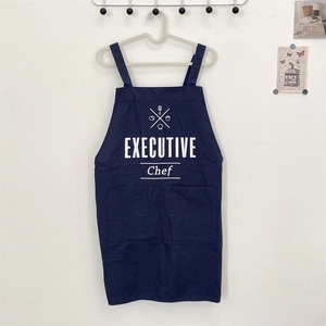 Detail of navy blue executive chef apron with front pockets and letter printing