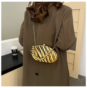 Detail of golden pleated leaf acrylic evening bag with beaded chain strap on shoulder