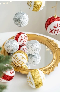 Close-up of sparkling gold and silver Christmas baubles with XMAS text on a golden tray
