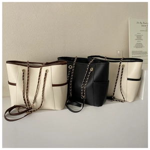 Detailed view of tote bags in cream and black featuring chain straps and side pockets