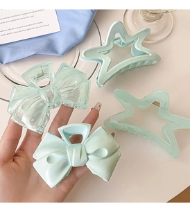 Close-up of cream blue bow and star-shaped hair claws in translucent and solid green resin