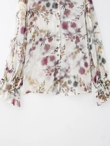 Dettaglio della camicetta in chiffon floreale con maniche a campana e fili metallici