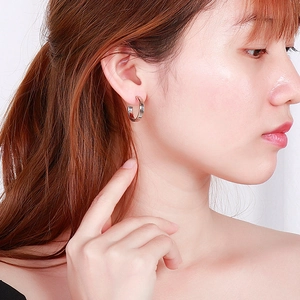 Detailed view of silver C-shaped stainless steel earrings on a female model with a polished finish
